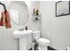 Small half-bathroom with pedestal sink, white toilet, and decor at 3828 Ramsay Pass, Loganville, GA 30052