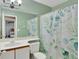 Bright bathroom with light green walls, a white vanity, and a shower with botanical-themed curtains at 3067 Nuptial Ln, Lawrenceville, GA 30044