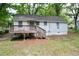 Back of the home featuring a wooden deck and white siding, surrounded by mature trees at 1025 Cheaves St, Forest Park, GA 30297