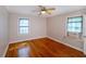 A traditional bedroom with hardwood floors, ceiling fan, and natural light from two windows at 1025 Cheaves St, Forest Park, GA 30297