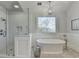 This bright bathroom offers a walk-in shower, stylish tub, tiled floors, and decorative window at 1830 Hadfield Blvd, Roswell, GA 30075