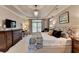 Bright main bedroom with a tray ceiling, dark wood furniture, and a chandelier at 1830 Hadfield Blvd, Roswell, GA 30075