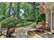 Stone patio with lounge chair and dining set, framed by lush greenery and mature trees at 1830 Hadfield Blvd, Roswell, GA 30075