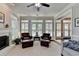 Bright sunroom features large windows, fireplace, two leather chairs, and ceiling fan at 1830 Hadfield Blvd, Roswell, GA 30075