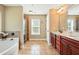 Bathroom with a tiled walk-in shower, soaking tub, and double sink vanity with cherry-wood cabinetry at 245 Tapestry Dr, Mcdonough, GA 30252