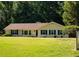 Single-story home with manicured lawn and mature trees and blue shutters at 2751 Colonial Dr, College Park, GA 30337