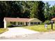 Well-maintained single-story home with blue shutters, a manicured lawn, mature trees, and a paved driveway at 2751 Colonial Dr, College Park, GA 30337