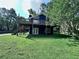 Charming two-story house with a wooden deck and stairs surrounded by lush greenery on a well-manicured lawn at 4464 Cary Dr, Snellville, GA 30039
