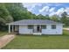 Inviting single-story home with a covered porch, updated windows, and a lush green lawn at 405 Emory St, Oxford, GA 30054
