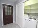 The laundry area is next to a brown front door, with a washing machine, dryer, and shelving in a closet at 175 Brookhaven Dr, Marietta, GA 30066