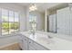 Bright bathroom featuring double sinks, large mirrors, a window with blinds, and a shower with a curtain at 310 Hammersmith Dr, Suwanee, GA 30024