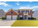 Charming two-story brick home with a well-manicured lawn, two-car garage, and inviting front porch at 310 Hammersmith Dr, Suwanee, GA 30024