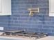 A modern gas cooktop with sleek gray countertops and an elegant blue subway tile backsplash at 4191 Hosch Reserve Dr, Buford, GA 30519