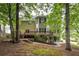The back of the house, featuring a deck and patio, is surrounded by lush trees at 1382 Benbrooke Nw Ln, Acworth, GA 30101