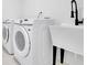 Modern laundry room with front loading machines, black faucet, and black farmhouse sink at 3165 Brookview Dr, Marietta, GA 30068