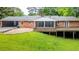 View of the rear exterior featuring a large, grassy backyard, a wooden deck, and a screened-in porch at 3916 Ridgewood Se Dr, Smyrna, GA 30080
