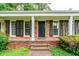 Close up of a brick front porch with black shutters, white columns and a black front door at 3916 Ridgewood Se Dr, Smyrna, GA 30080