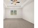 Spacious primary bedroom with neutral carpet, large windows offering serene views, and a modern ceiling fan at 648 Kimberwick Dr, Locust Grove, GA 30248