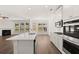 Open kitchen with stainless steel appliances, white cabinetry, island with sink, and luxury vinyl plank flooring throughout at 1871 Lacebark Elm Way Way, Lawrenceville, GA 30045