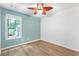 Bright bedroom features a ceiling fan, wood-look floors, and a window with views of the outdoor greenery at 2700 White Blossom Ln, Suwanee, GA 30024