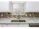 Well-lit kitchen with stainless steel sink, granite countertops, and stylish backsplash at 820 Tradd Ct, Stone Mountain, GA 30087