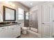 Well-lit bathroom featuring a glass shower, dark countertop, wood framed mirror and gray tile flooring at 7575 Old Camp Lndg, Cumming, GA 30040