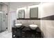 Well-lit bathroom featuring double sinks, dark wood cabinets, and tiled floors and shower with glass door at 1120 Arlington Sw Ave, Atlanta, GA 30310