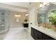 Bathroom with tiled shower, double sink vanity, and arched window with natural light and wooded view at 818 Forest Path Ln, Alpharetta, GA 30022