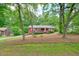 Red home nestled among mature trees and lush greenery, offering a serene and private setting at 2900 Country Nw Ct, Kennesaw, GA 30152