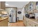 Cozy kitchen featuring wood floors, stainless steel refrigerator, cabinets with photo display, and modern microwave at 483 Glen Terrace Rd, Auburn, GA 30011