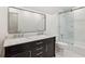 Bathroom featuring a double sink vanity, marble counter, black cabinets, and glass shower at 200 River Pass Trl, Atlanta, GA 30350