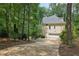 Back exterior of home with driveway, garage and surrounded by lush green trees at 200 River Pass Trl, Atlanta, GA 30350