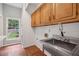 Bright laundry room features wood cabinets, stainless steel sink, faucet, and hardwood floors at 200 River Pass Trl, Atlanta, GA 30350
