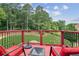 Inviting back deck with red chairs and a wrought iron railing overlooking a large, wooded backyard at 3364 Kylee Dawn Cir, Lawrenceville, GA 30045