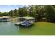 Image shows a covered boat dock with a boat inside on a lake surrounded by trees at 4940 Sunrise Ln, Cumming, GA 30041
