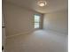 Spacious carpeted bedroom with a window providing natural light and neighborhood view at 5685 Kingsport Dr, Sandy Springs, GA 30342
