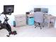 Home office setup with exercise bike, desk, monitors, storage drawers, and comfortable chair at 5790 Thornton Dr, Cumming, GA 30028