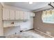 A laundry room featuring unfinished walls, tile flooring, cabinets and a window at 3898 Bay Creek Rd, Loganville, GA 30052