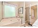 Soaking tub and shower featuring tiled surround, frosted window, and decorative accents at 90 Camden Woods Pl, Dallas, GA 30157