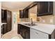 Functional kitchen featuring dark wood cabinets, stainless steel sink, and adjacent dining area with sliding glass doors at 90 Camden Woods Pl, Dallas, GA 30157
