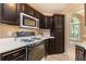 Efficient kitchen layout featuring dark wood cabinets, white countertops, and modern appliances, maximizing space and functionality at 90 Camden Woods Pl, Dallas, GA 30157
