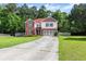 Charming two-story home with red door, a two-car garage, mature trees, and a long driveway at 3235 Avondale Pkwy, Powder Springs, GA 30127