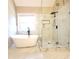 Luxurious bathroom featuring a freestanding tub, glass-enclosed shower with rainfall showerhead, and marble tiling at 5705 Cannonero Dr, Alpharetta, GA 30005