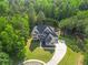 Birds-eye view of a luxury home, showcasing its well-manicured lawns, long driveway, and lush surrounding landscape at 3298 Alcovy Club Ct, Dacula, GA 30019