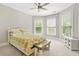 Bright bedroom with large windows, ceiling fan, and a cozy bed with yellow patterned bedding offering a serene and inviting retreat at 3298 Alcovy Club Ct, Dacula, GA 30019