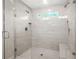 Modern tiled shower with glass door, dual shower heads, built-in niche, and a window for natural light creating a spa-like experience at 3298 Alcovy Club Ct, Dacula, GA 30019