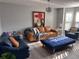 Bright living room featuring a leather sofa, a blue cushioned ottoman, and a modern chandelier at 5536 Strathmoor Manor Cir, Lithonia, GA 30058
