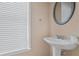 Powder room features pedestal sink, round mirror, and natural light from the window at 7812 Kiverton Pl, Atlanta, GA 30350