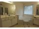 Bright bathroom with a corner tub, dual vanities and natural light from a window at 442 John Stewart Pl, Suwanee, GA 30024