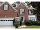 Charming red brick two-story home with manicured lawn and attached two car garage at 442 John Stewart Pl, Suwanee, GA 30024